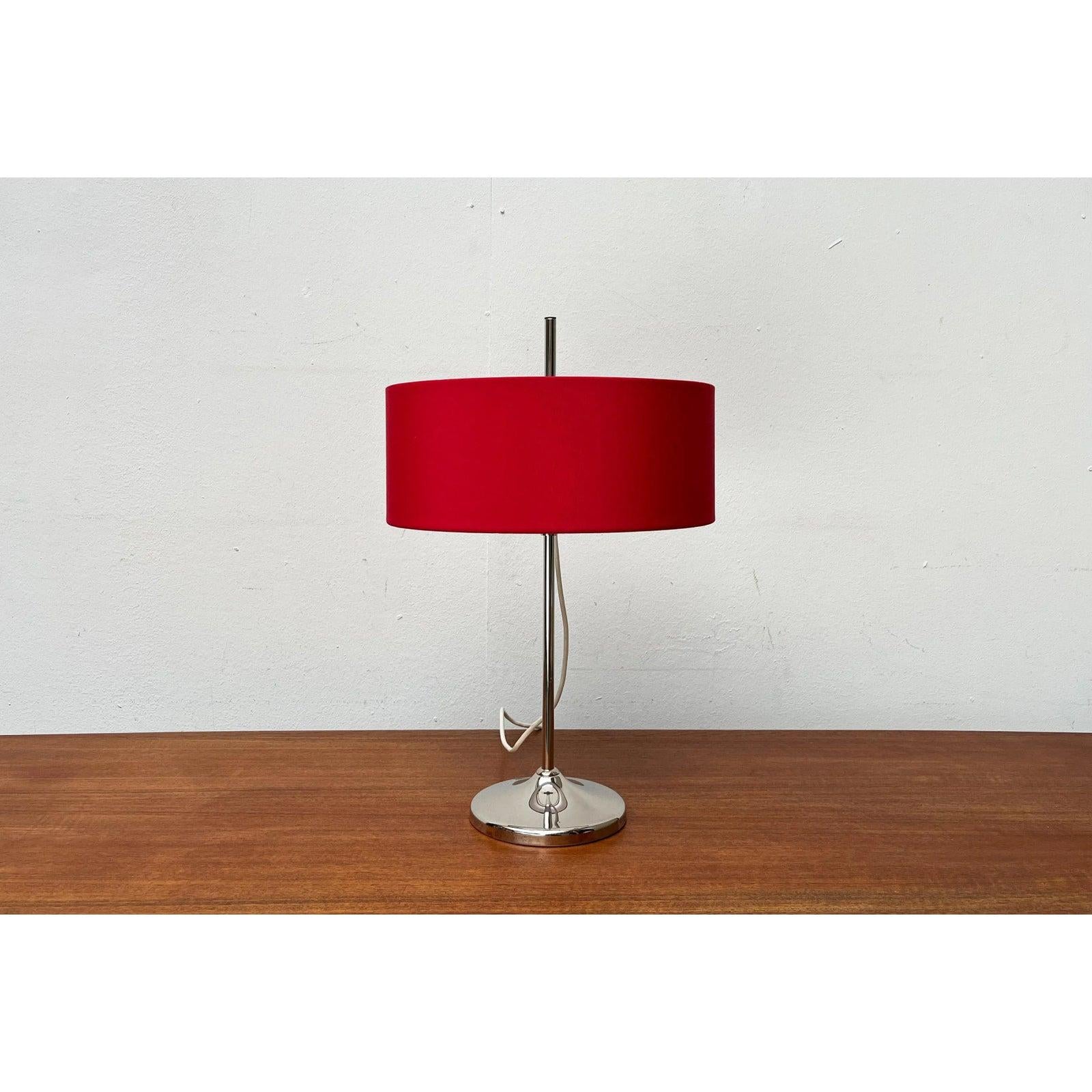 Lampe de table du milieu du siècle avec abat-jour rouge.

L'abat-jour tambour simple est recouvert de rouge et possède un toit en parchemin blanc. Il peut être déplacé vers le haut et vers le bas de l'arbre pour modifier l'effet d'éclairage et
