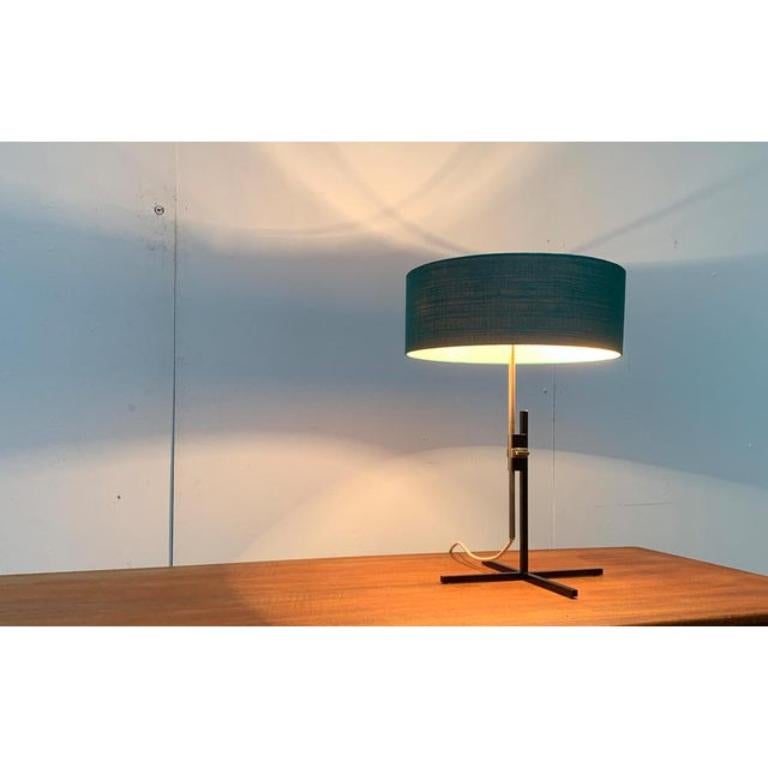 Rarissima lampada da tavolo del Mid Century di Kaiser lights con un particolare piede minimalista.

Il dettaglio speciale di questo apparecchio è il semplice piede a stella di colore nero, formato da aste quadrate, che difficilmente supera la