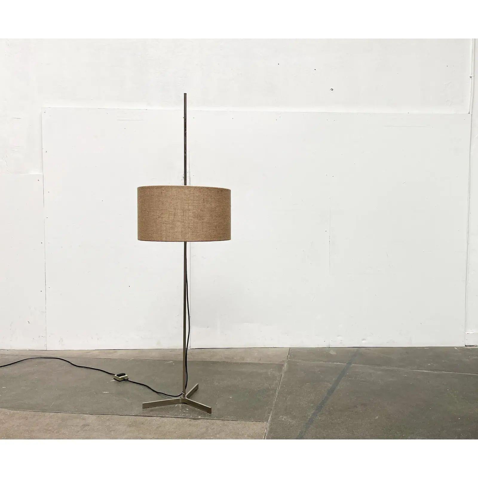 Lampada da terra di metà secolo con base e paralume particolari.

Il dettaglio particolare di questa lampada è la semplice base a treppiede. Il paralume a forma di tamburo è ricoperto da un pesante materiale di juta. Può essere spostato verso l'alto