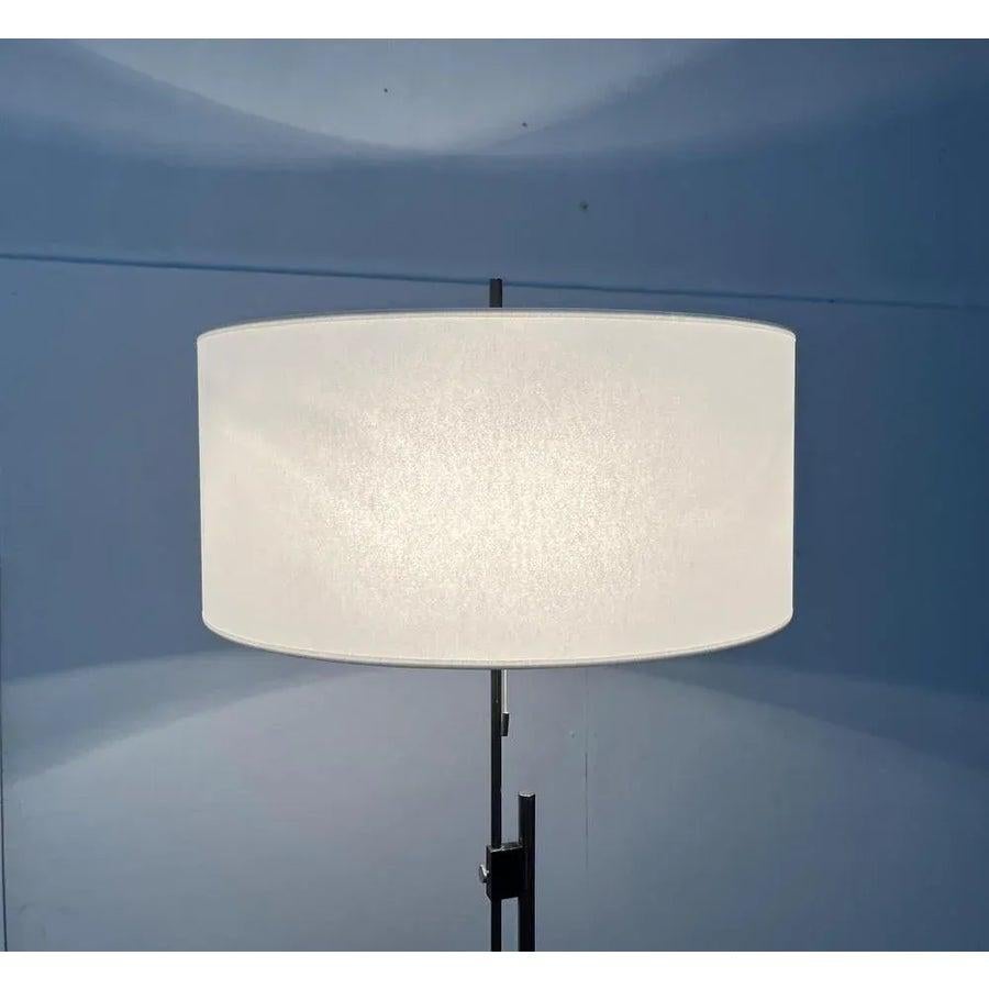 Lampada da terra di metà secolo con ombrello regolabile in altezza e un piede speciale.

un design minimalista. Il dettaglio speciale di questa lampada è il semplice piede a tre gambe. Un ombrello a forma di tamburo, ricoperto di pergamena bianca,