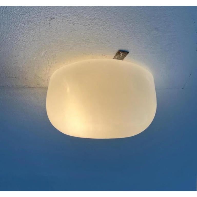 Minimalist mid-century ceiling or wall light from the German manufacturer BUR Leuchten.

The glass has a simple but striking egg shape with gentle curves. The base is not visible. It has a mechanism to lock the glass from the front. The lamp is in