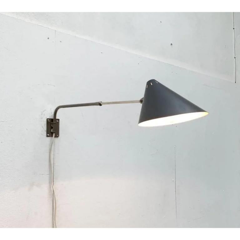 Rara lampada da parete di Hala.

un design minimalista che difficilmente può essere superato in termini di funzionalità. La testa dell'apparecchio forma un imbuto asimmetrico dipinto in grigio scuro. Il paravento è collegato all'albero tramite un