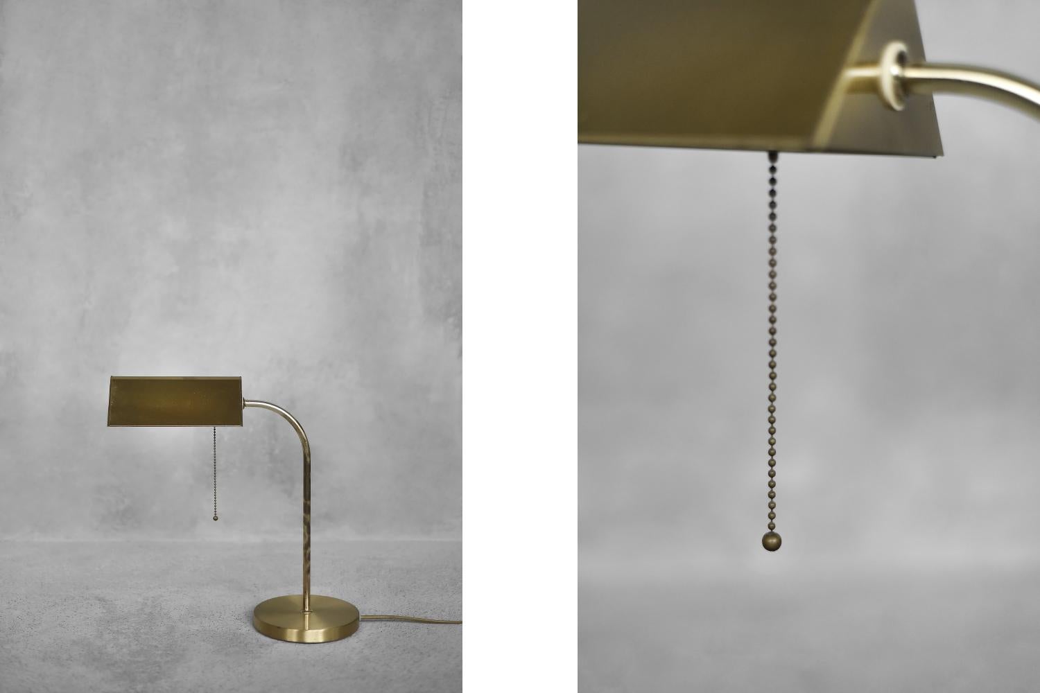 This elegant, brass banker-type desk lamp was produced by the German manufacturer Karstadt AG in the 1970s. It is made of brushed brass with a truly classic look. It has a geometric lampshade with an inclined shape. The switch is placed on a metal