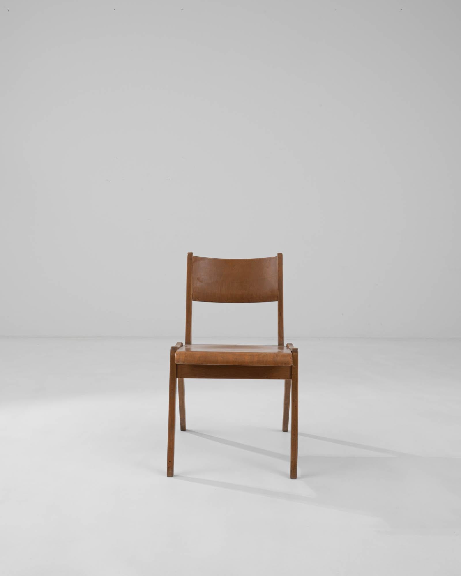 The simple yet striking form of this Modernist wooden dining chair cuts a stylish silhouette. Built in Germany in the 20th century, the clean slant of the A-frame legs is echoed in the reclined angle of the back rail, creating a graphic composition.