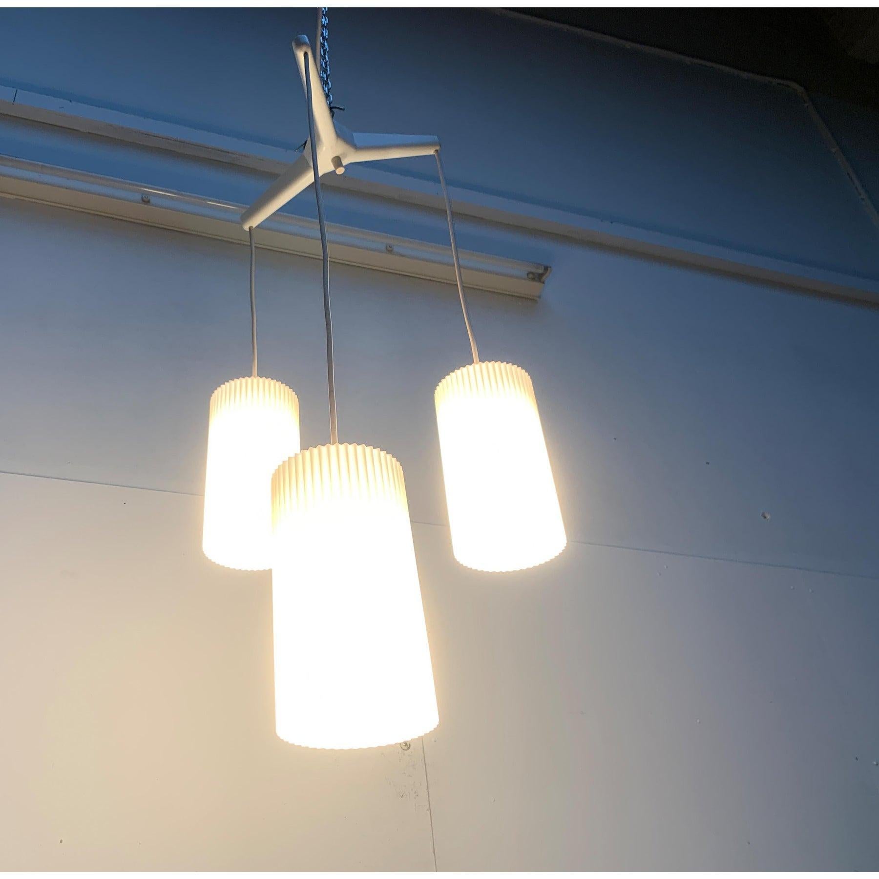 Lampada a sospensione a cascata del Mid Century di Erco.

I paralumi cilindrici sono realizzati in plastica traslucida e presentano una superficie scanalata. Sono appesi a diverse altezze. La parte della presa con la sospensione è semplicemente