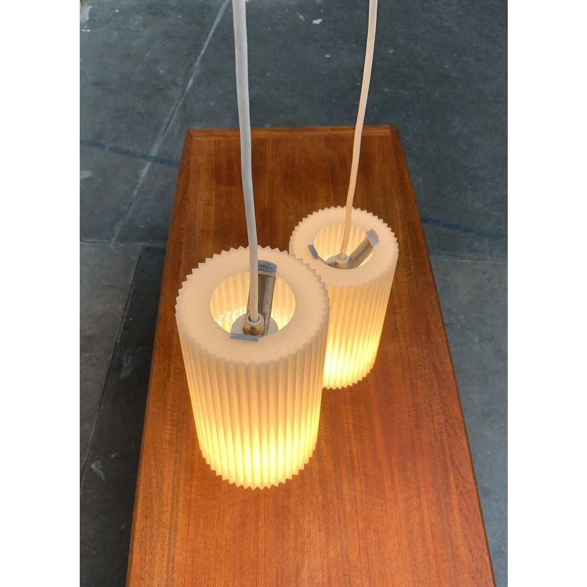 Sleek Mid Century pendant lights from Erco.

A minimalist design. The diffusers are made of plastic and fluted all around. The suspension with the socket is fixed with a clamp in the upper opening of the shade. I have official proof of authenticity