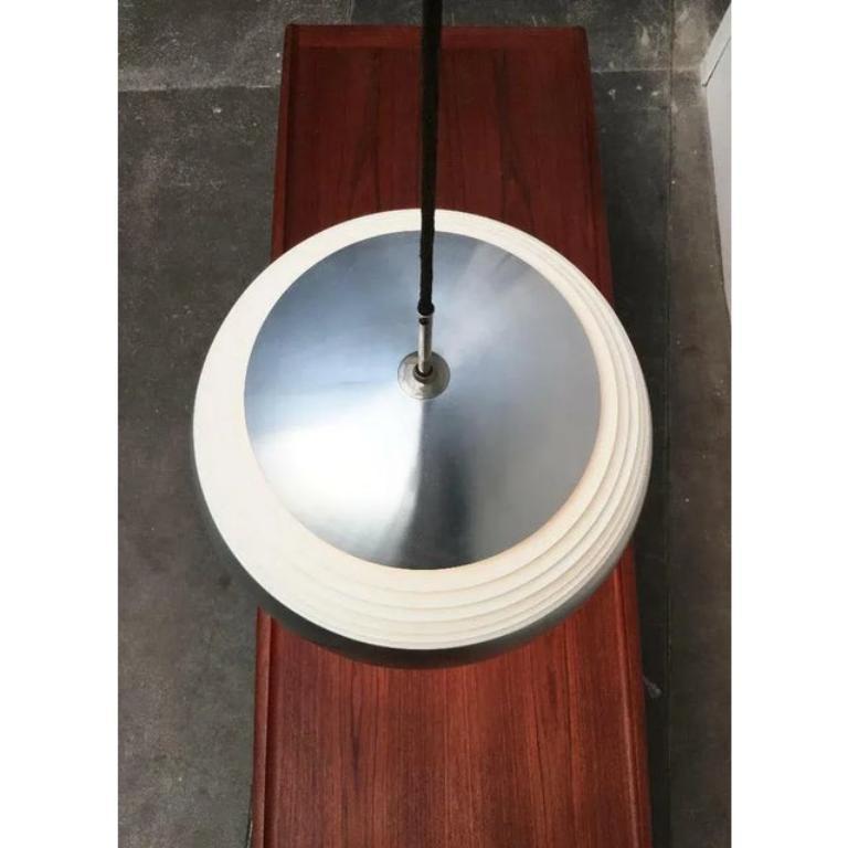 Rara lampada a sospensione a forma di louvre di Doria, risalente alla metà del secolo scorso.

La lampada ha una classica forma a cupola. La sezione centrale è suddivisa in lamelle piatte. Con un diametro di 45 cm, è uno dei pendenti più grandi.