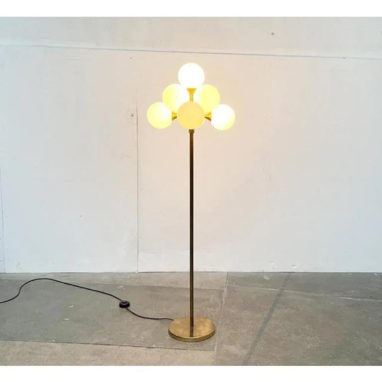 Imposante lampe sur pied NO AGE en laiton et verre.

Source de lumière fonctionnelle et en même temps objet lumineux dans la pièce. Le corps de lampe en forme de raisin se trouve à l'extrémité supérieure d'une longue tige qui se termine par un