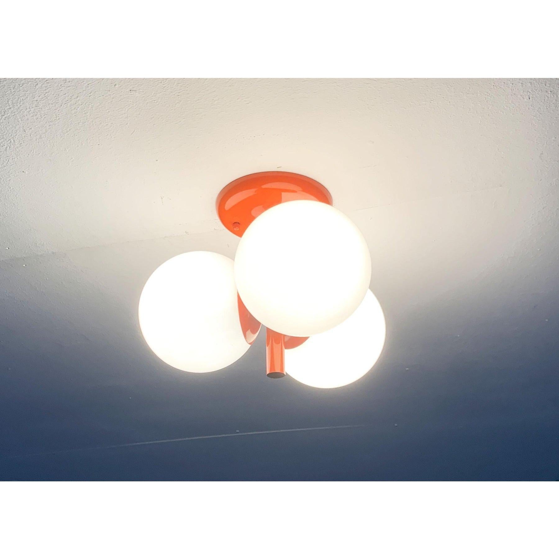 Imposant plafonnier ou applique murale de Kaiser lights dans une couleur spéciale, datant de l'ère spatiale.

Le corps central du Luminaire est conservé en orange. L'arbre mince descend dans une plaque en forme de trompette. Les diffuseurs en verre