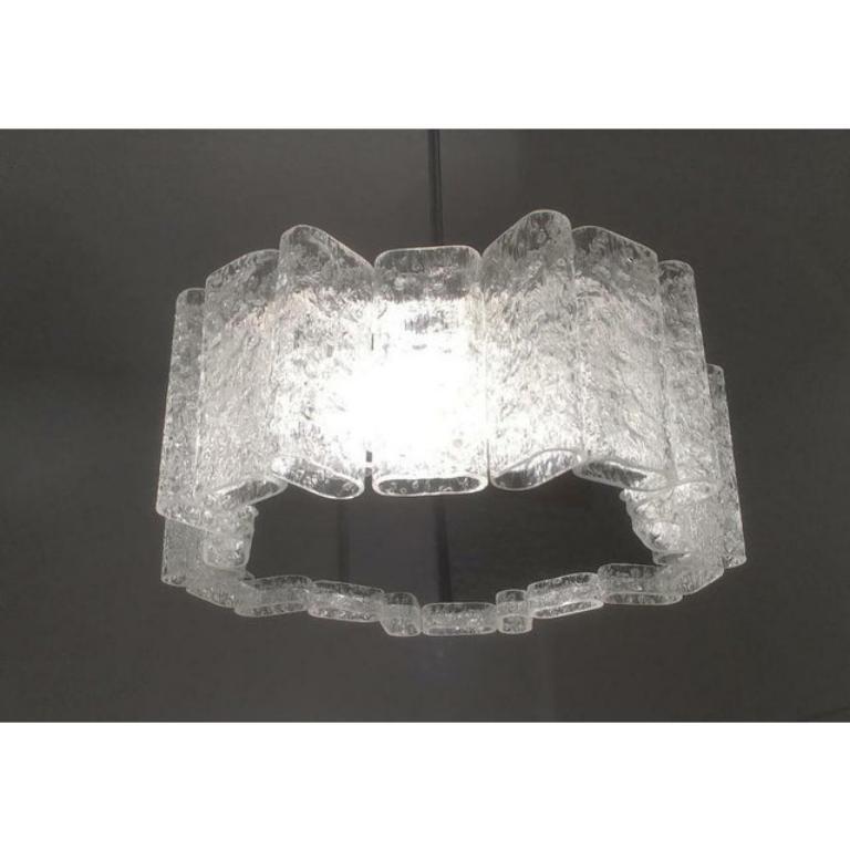 Imponente lampada in vetro del rinomato produttore Doria Leuchten.

Gli elementi di vetro strutturale rompono e potenziano la luce delle due lampade all'interno. Questo li rende una lampada funzionale e un oggetto luminoso in uno. I 20 elementi in