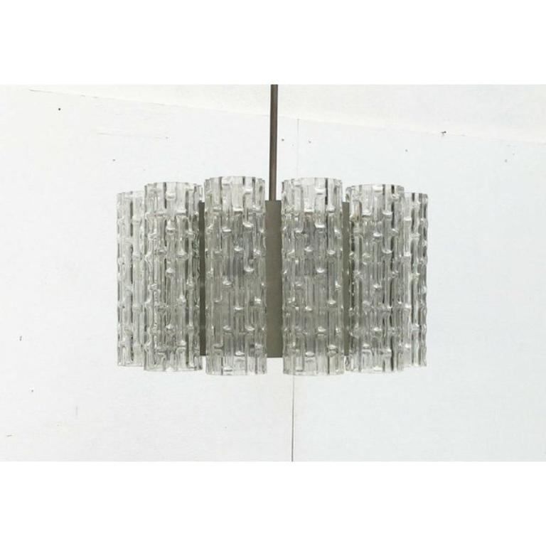 Imponente candeliere del rinomato produttore Doria Leuchten.

Gli elementi di vetro strutturale si rompono e potenziano la luce della lampada all'interno. Questo li rende una lampada funzionale e un oggetto luminoso in uno. Gli elementi in vetro