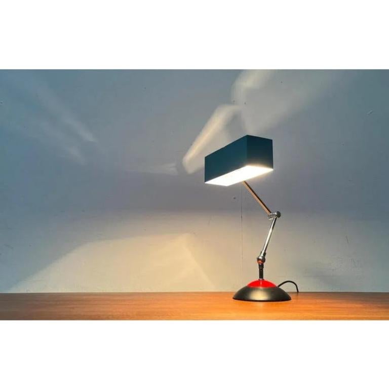 Farbige Tischleuchte aus der Mitte des Jahrhunderts vom deutschen Hersteller Hoffmeister Leuchten.

Der Lichtkopf hat die Form eines einfachen Quaders, der auf der Unterseite offen ist. Die Kanten an der Oberseite sind als Fugen gestaltet, durch die