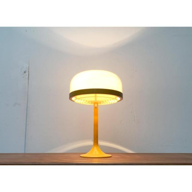 Raras lámparas de mesa de Kaiser Leuchten.

Forma de luminaria clásica con pie central en forma de tulipa. El pie metálico es de un amarillo intenso, la capucha difusa de acrílico es blanca y translúcida. En la parte superior, la capucha blanca