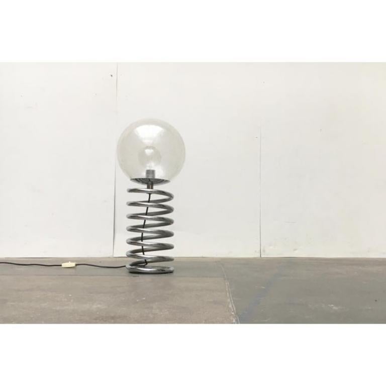 Imposant lampadaire ou lampe de table Spiral Bulb du designer d'éclairage Ingo Maurer.

Un diffuseur sphérique trône sur une spirale massive chromée. Le verre est structuré, ce qui donne à la lumière un effet particulier. La lourdeur du Luminaire