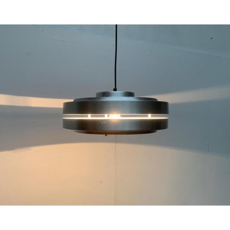 Semplice lampada a sospensione Ufo dell'era spaziale.

Il design minimalista sorprende quando è acceso con un imponente effetto luminoso. Il corpo piatto del Luminaire è composto da due parti collegate separatamente da distanziatori poco visibili