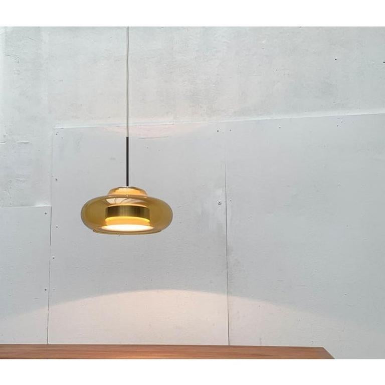 Impressionante lampada a sospensione in vetro del rinomato produttore Doria Leuchten.

Un gioco con trasparenza e forma. Il vetro giallo trasparente forma la forma esterna, rivelando i diversi livelli e il complesso interno del corpo della lampada.