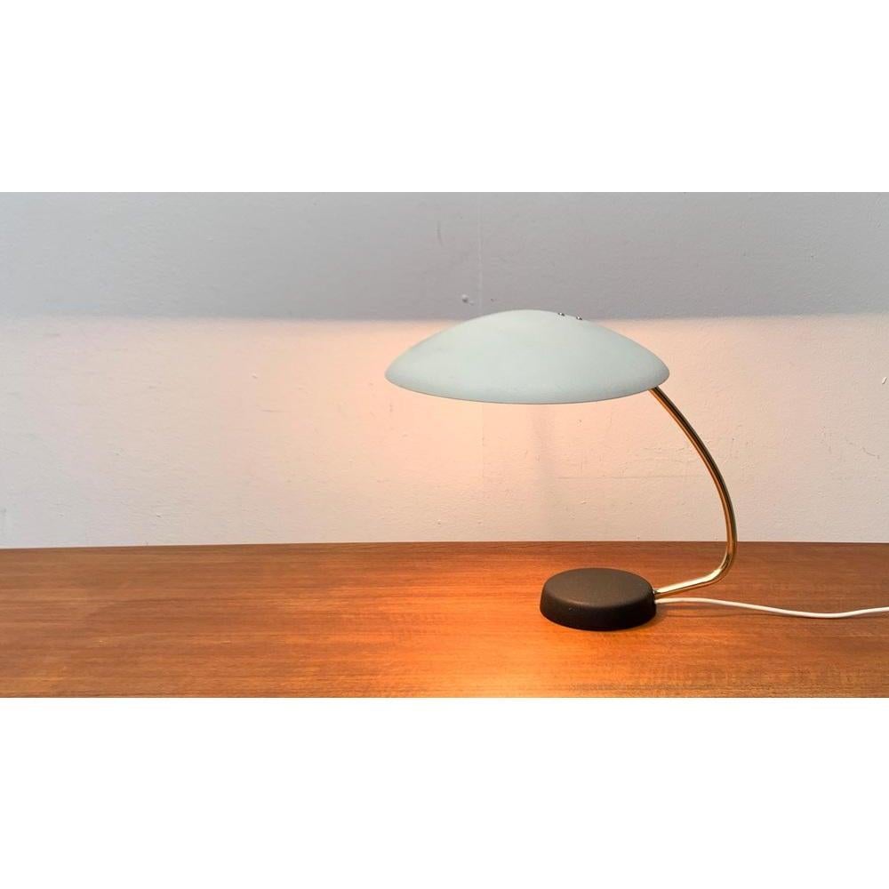 Elegant table lamp from Cosack from the 1960s.

A simple and functional design. The flat umbrella is connected to the foot via a widely curved stance made of brass. The umbrella can be tilted over a joint and also turned on a small radius. It is