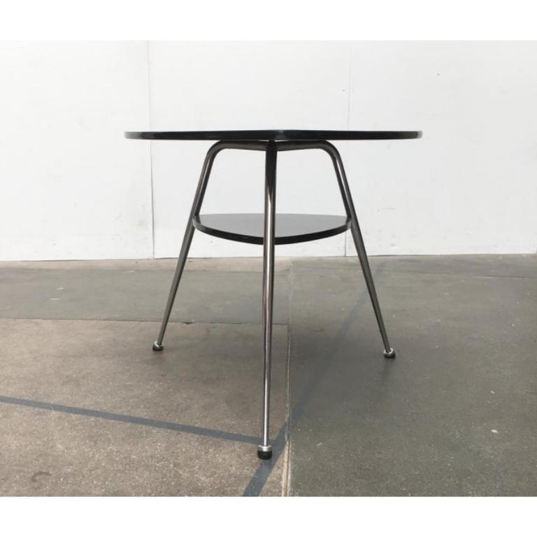 Table Mauser en acier tubulaire d'une forme et d'une couleur particulières.

Outre la forme triangulaire caractéristique, c'est surtout le revêtement bleu-gris des surfaces de la table qui attire l'attention. Le bord en plastique noir contraste avec