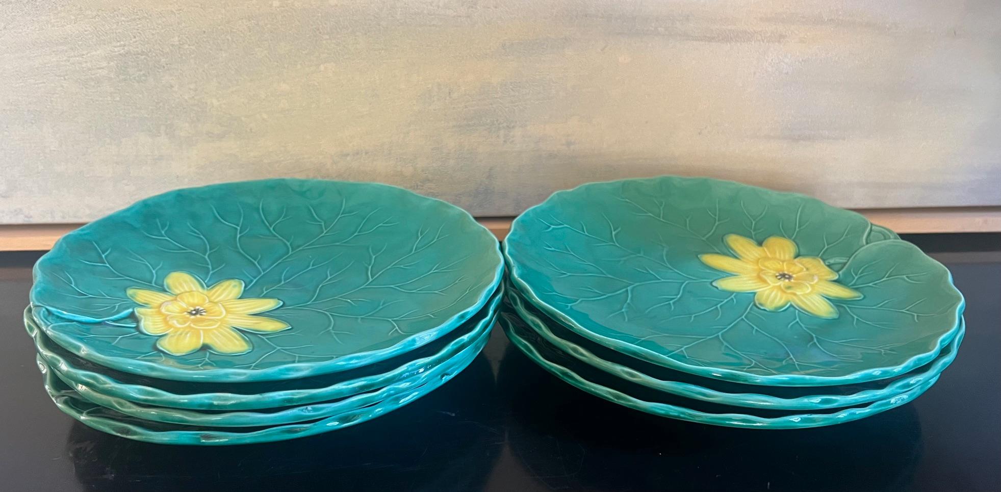 Ensemble de huit assiettes en majolique fabriquées à Zell am Harmersbach en Allemagne vers le milieu du 20e siècle. Les assiettes peintes à la main ont des bords festonnés qui s'inclinent vers le haut. Elles sont ornées d'une feuille vert vif et