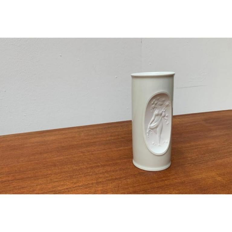 Elegant, white porcelain vase based on a design by Bjørn Wiinblad from the 60s. The decor is inset shows a fine relief with matte finish. This piece has an attribution mark, It is completely authentic for any authenticity issues arising from