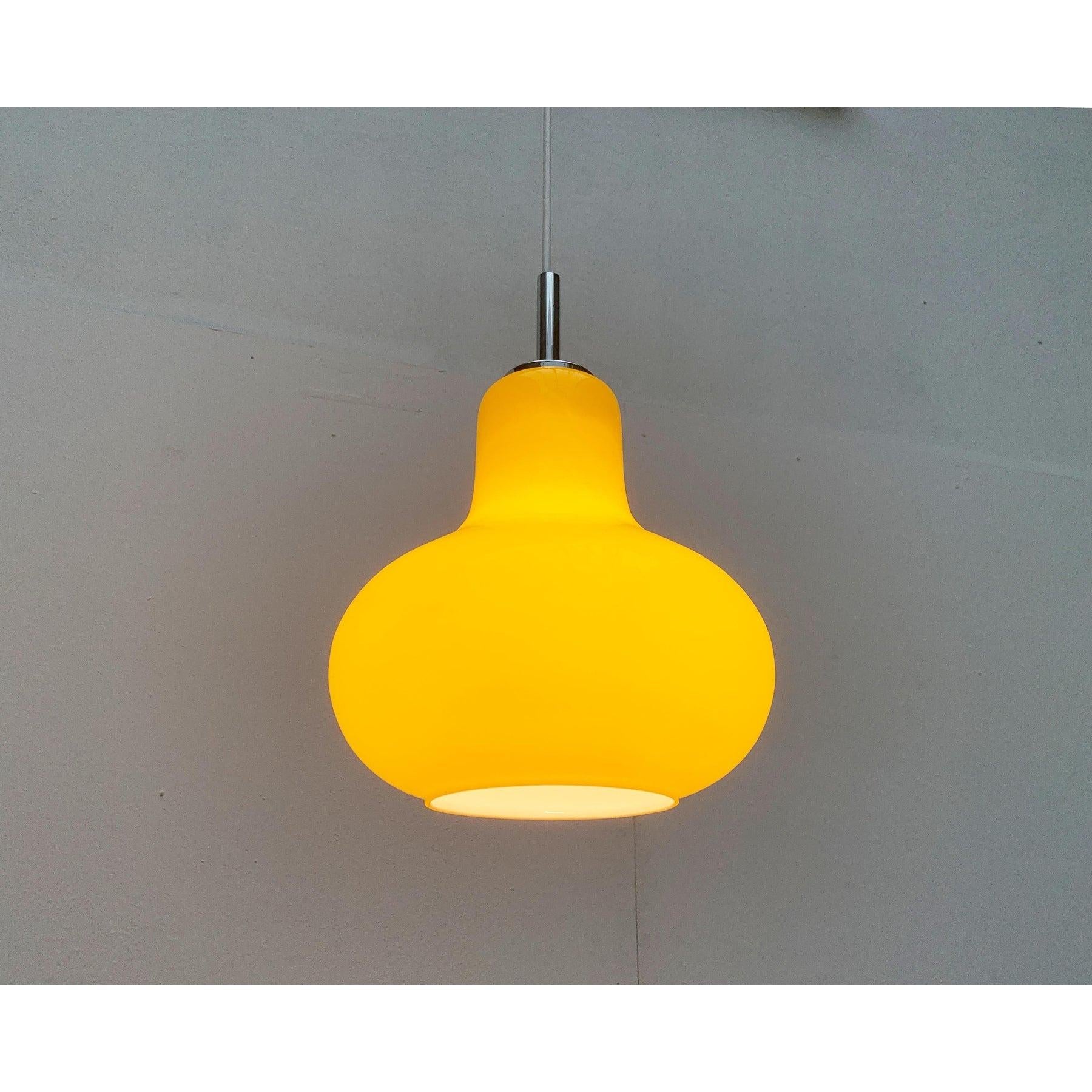Semplice lampada a sospensione in vetro del Mid Century di colore giallo.

Il corpo luminoso in vetro è a forma di pera e di colore giallo rovesciato. La parte della presa è dotata di uno speciale sistema di stiratura pieghevole e mantiene il corpo