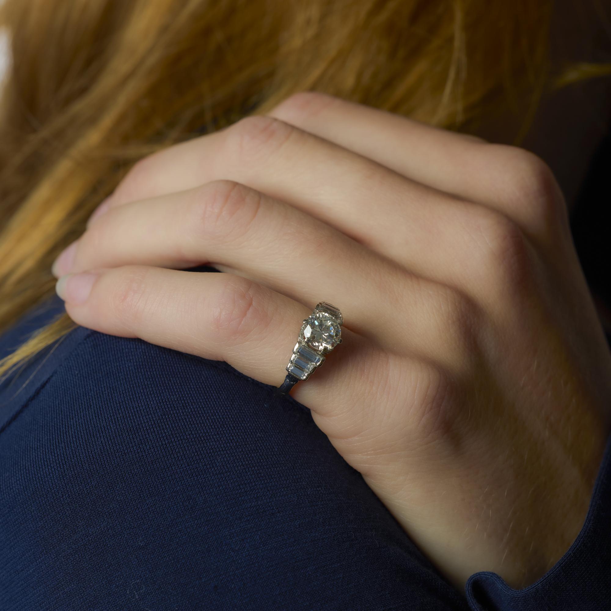 This Mid Century platinum and 14k white gold ring centers a 1.52 carat diamond, flanked by sleek baguette diamonds for timeless elegance and vintage character.