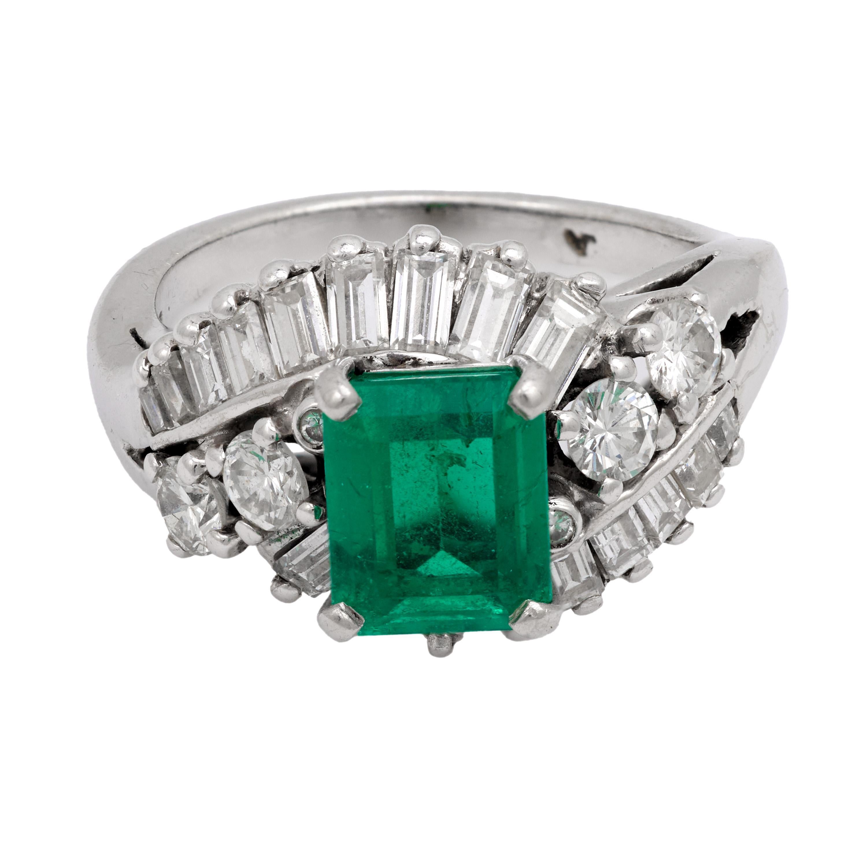 A stunning 1950s Mid Century ring showcasing a vibrant Colombian emerald framed by sparkling baguette and round diamonds in luminous 14k white gold.