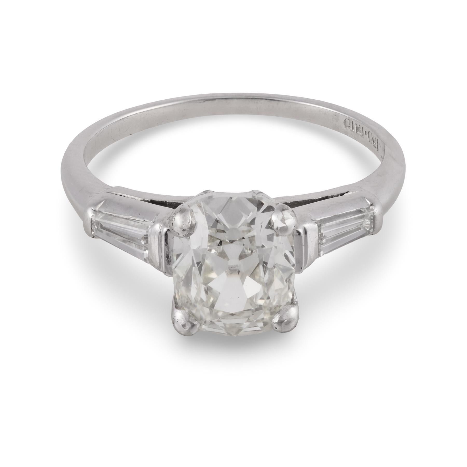 Cette bague en platine du milieu du siècle met en valeur un diamant lumineux taillé dans une ancienne mine, encadré par des baguettes effilées, mêlant le romantisme vintage à la sophistication intemporelle dans une silhouette raffinée et sculpturale.