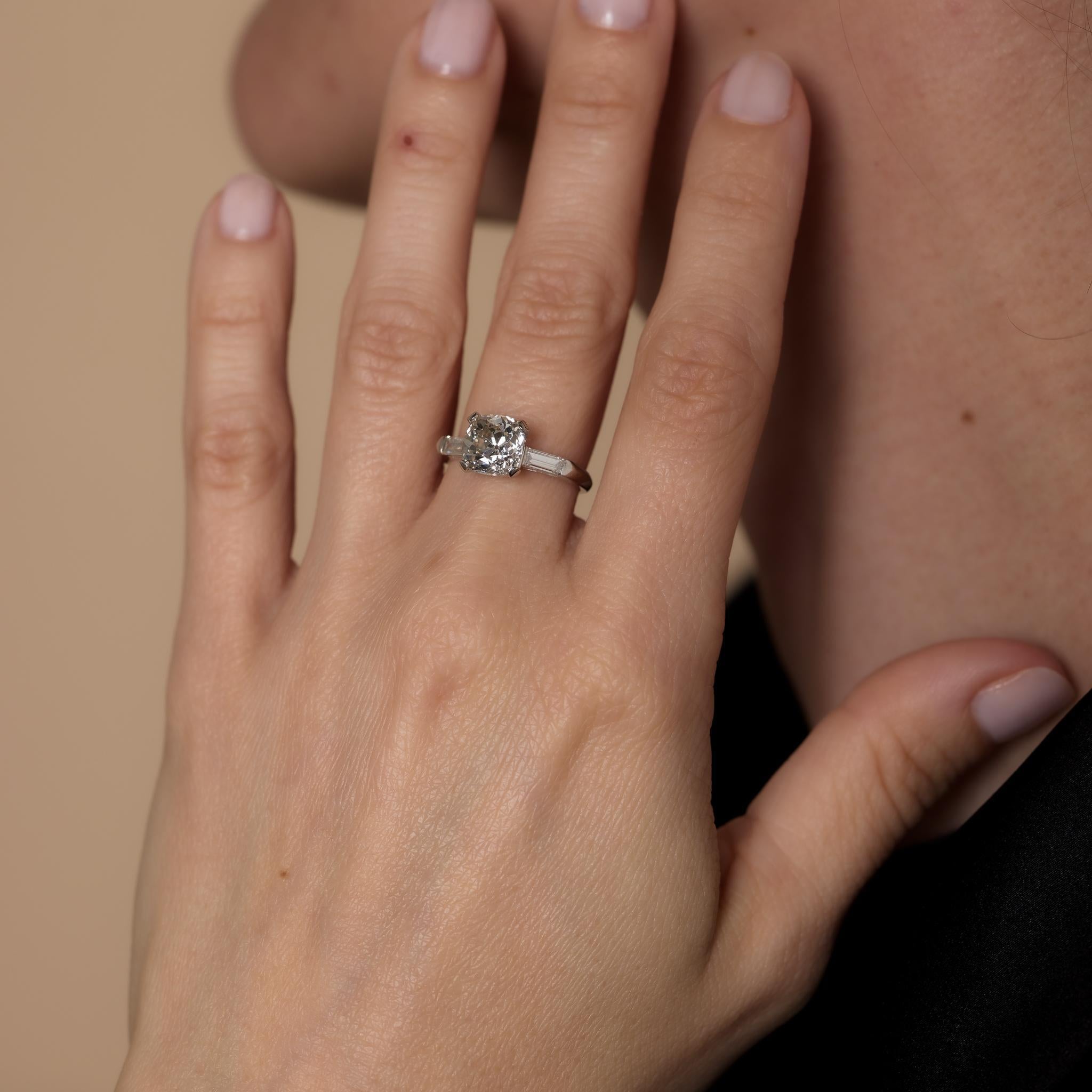 This Mid-Century platinum engagement ring showcases a GIA-certified 2.37-carat old mine cut diamond (J color, VS2 clarity), accented by two baguette cut diamonds totaling .20 carats, J-K color, and VS clarity. Crafted in the 1960s, it is hallmarked