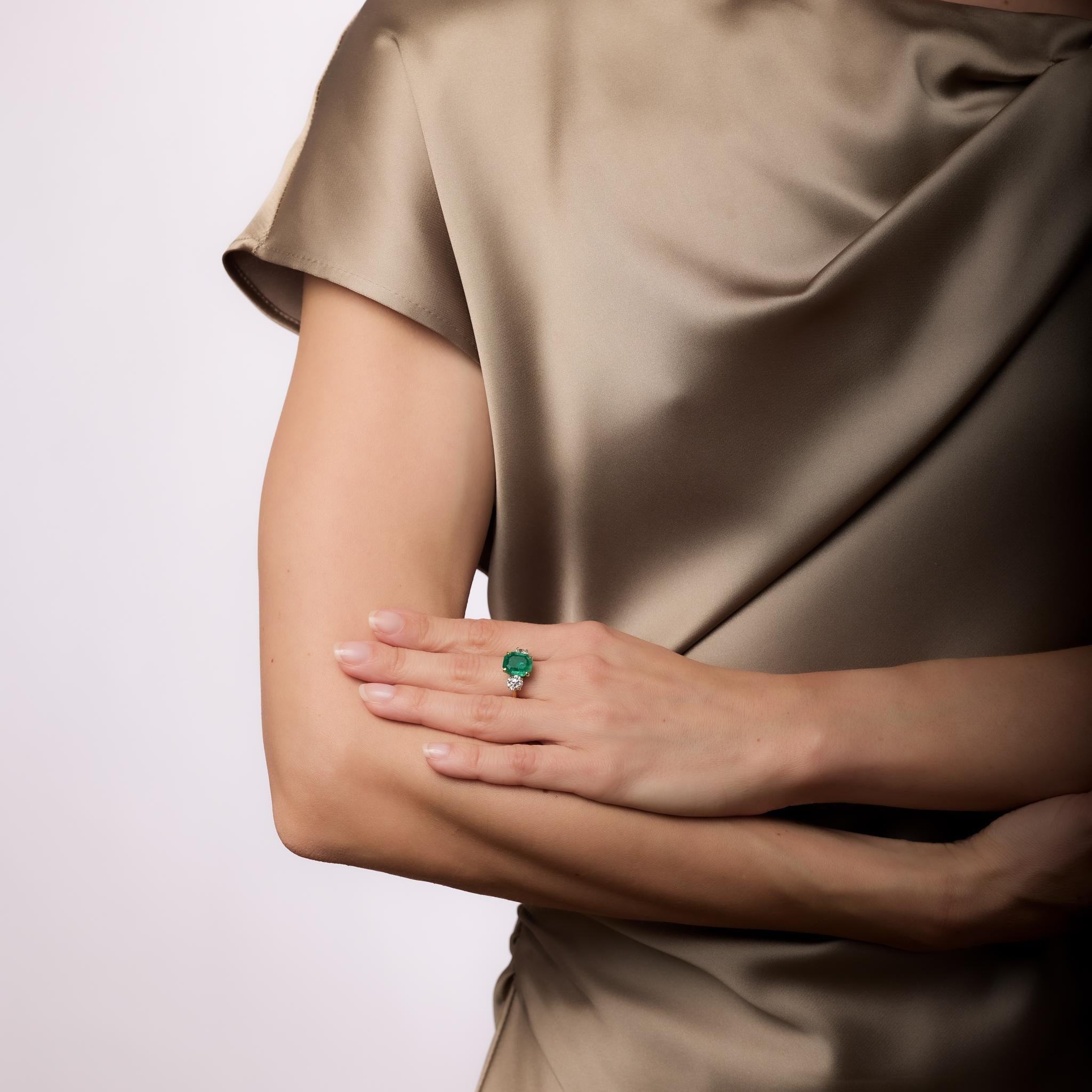 Cette bague en or jaune 18k du milieu du siècle présente une émeraude colombienne de 3,25 carats certifiée par le GIA, de taille émeraude, traitement F2, flanquée de deux diamants de taille européenne ancienne totalisant environ 1,20 carats, couleur