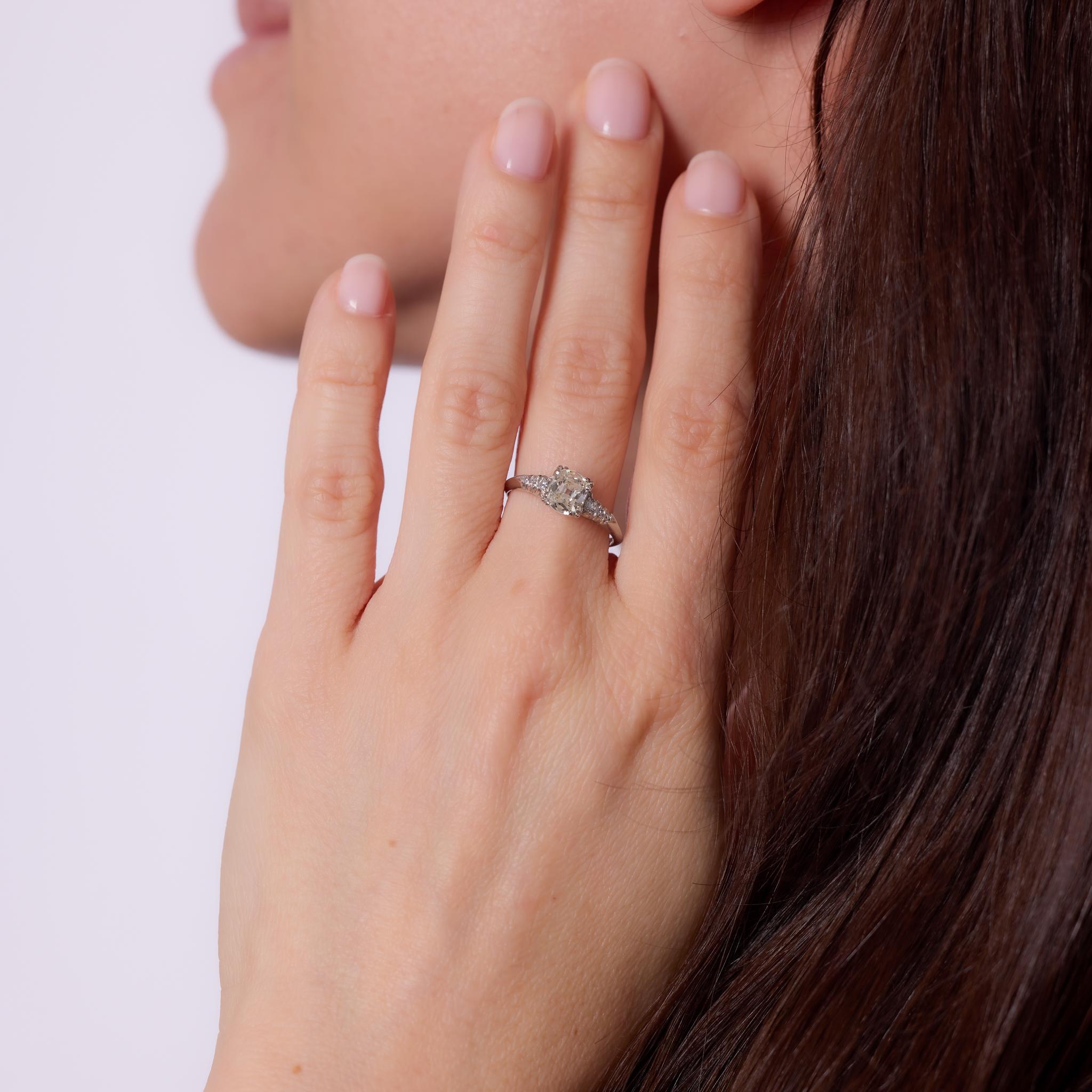 Crafted in the 1950s, this Mid Century engagement ring features a GIA-certified .90-carat old mine cut diamond, graded L color and SI1 clarity, offering a warm glow and distinctive antique charm. Six single cut diamonds totaling approximately .10