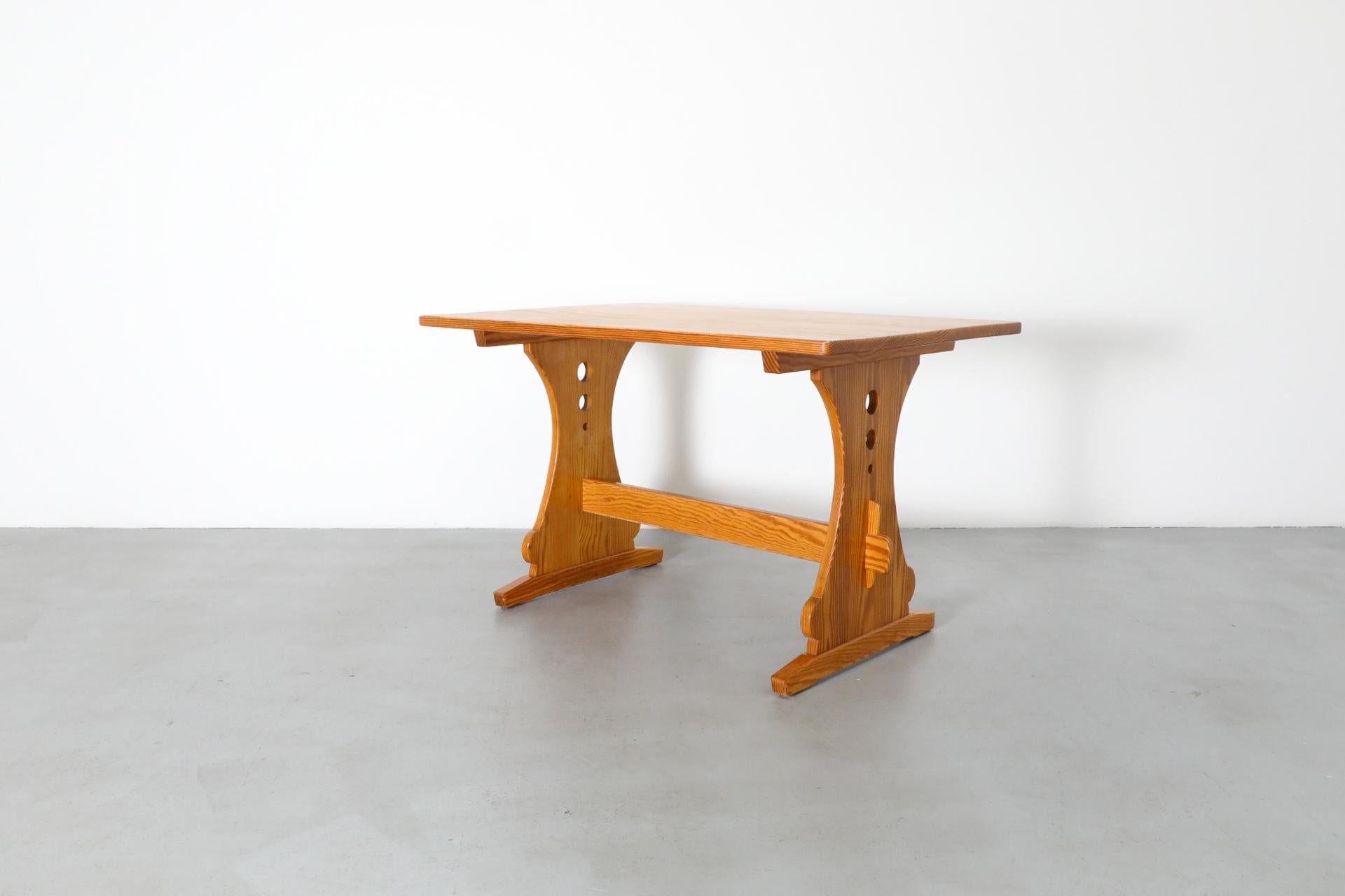 Mid-Century Gilbert Marklund style pine dining table with ornate trestle base and circle cut-out detail. An attractive and versatile table that can be used as in an entryway, or as a desk, vanity or small dining table. In original condition with