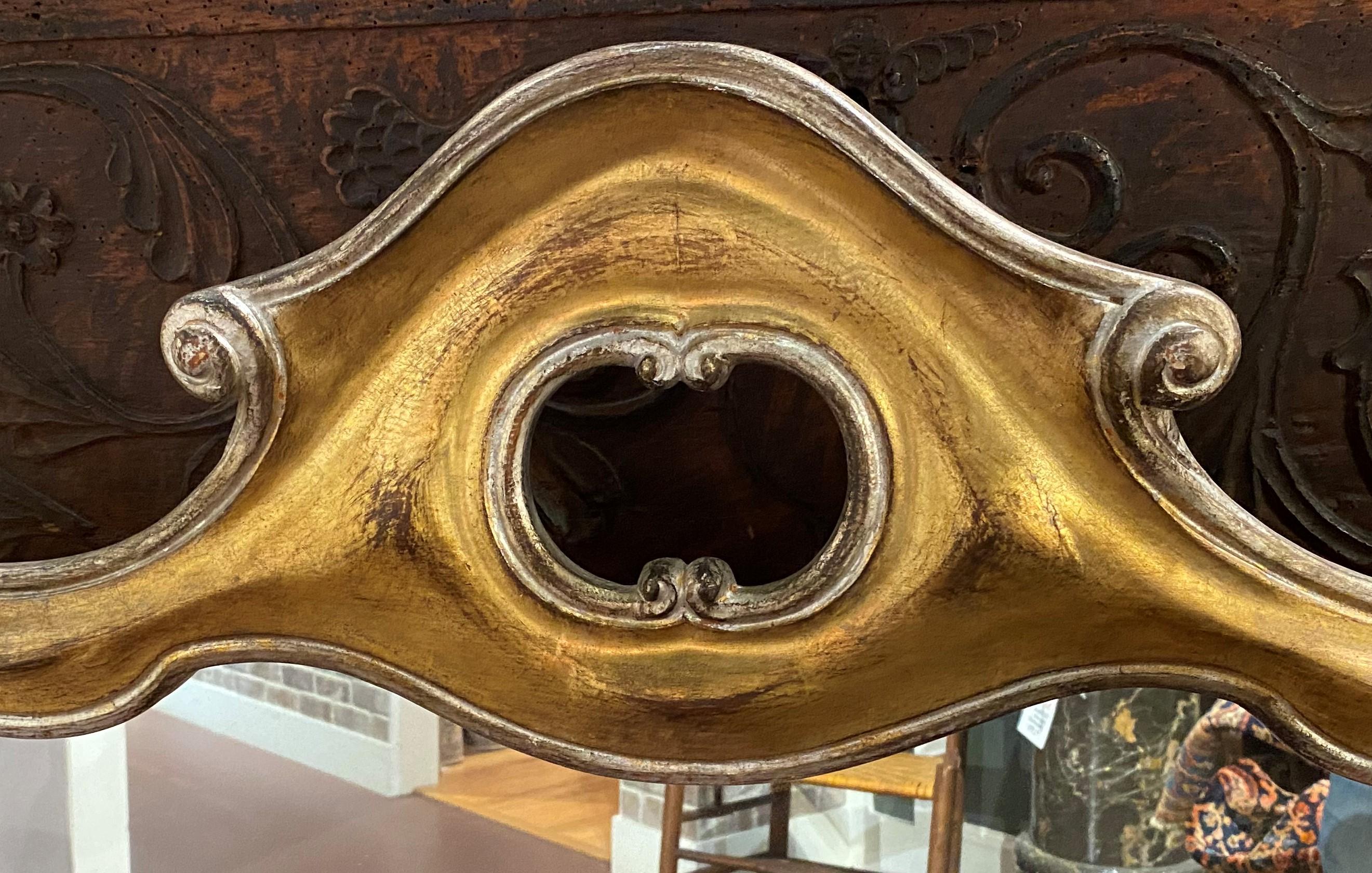 A fine shaped mid century gold and silver gilt gilt carved wooden frame wall mirror with scrollwork edge and simple pierced crest. Italian in origin, dating to the 1960’s. Perfect for the end of a hallway or even over a small mantle. Very good