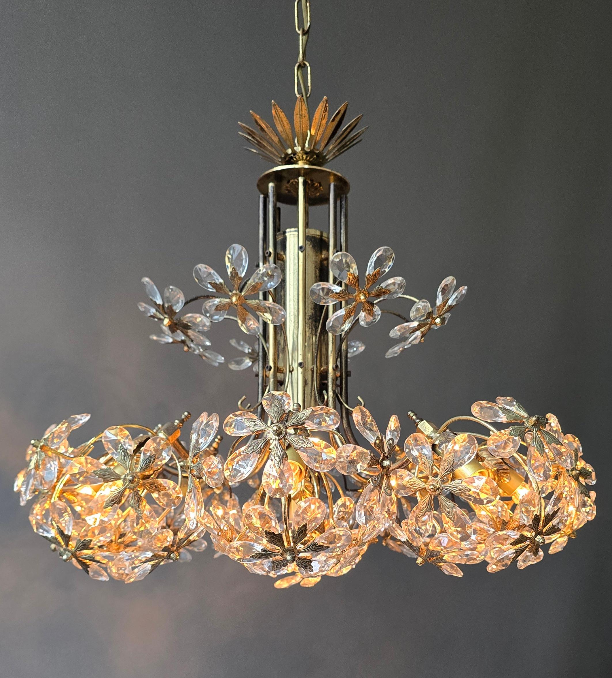 Un luxueux lustre floral du milieu du siècle attribué à Palwa, Munich, vers 1960. Neuf groupes de lumières sculpturales avec des pétales de cristal taillés à la main et montés sur des éléments floraux raffinés en laiton doré. Le lustre émet un éclat