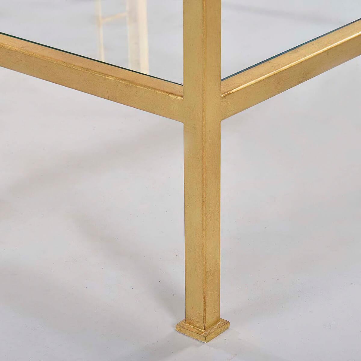 Midcentury style rectangle coffee table with clear tempered glass top and shelf, straight legs, and portrait frame detail on the table sides, has a “gold leaf” finish on a steel frame.

Dimensions: 48