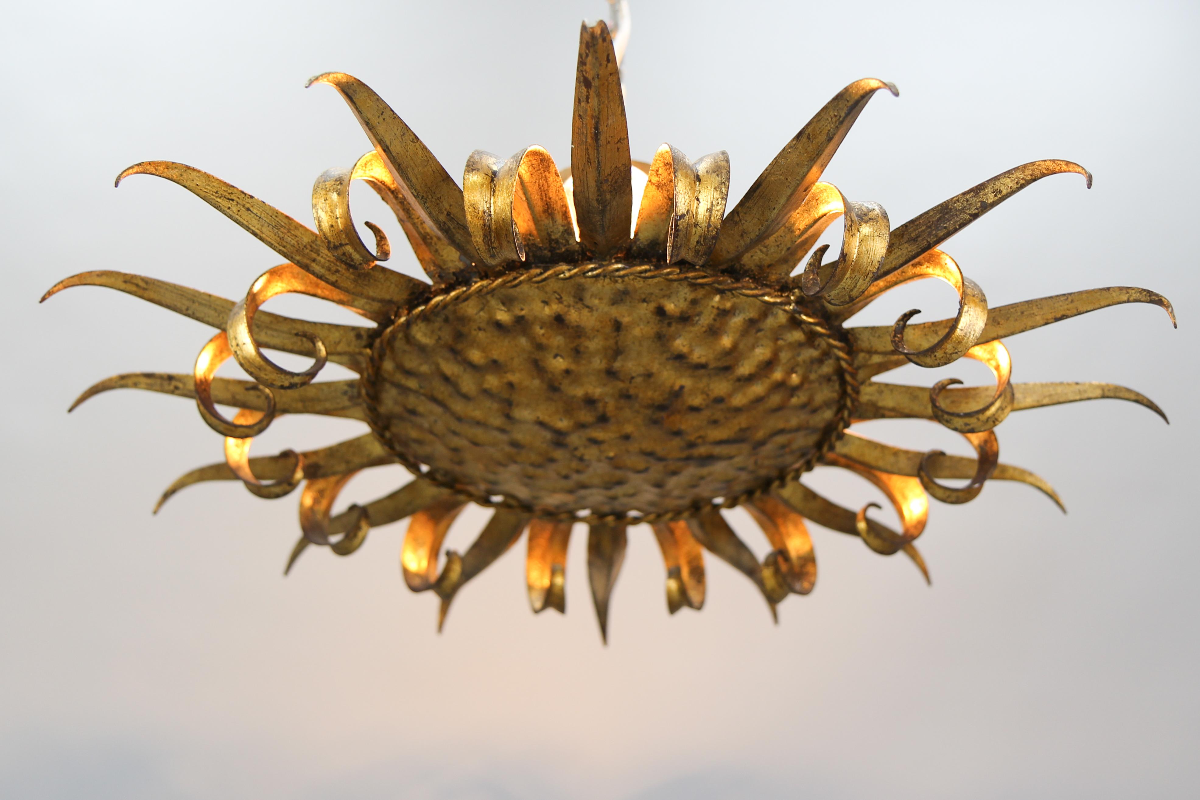 Plafoniera a forma di sole in metallo dorato di metà secolo, Spagna, anni '50 circa.
Questa bellissima plafoniera a forma di sole del periodo Mid-Century Modern è caratterizzata da un unico livello in metallo dorato con raggi curvi e dritti o motivo