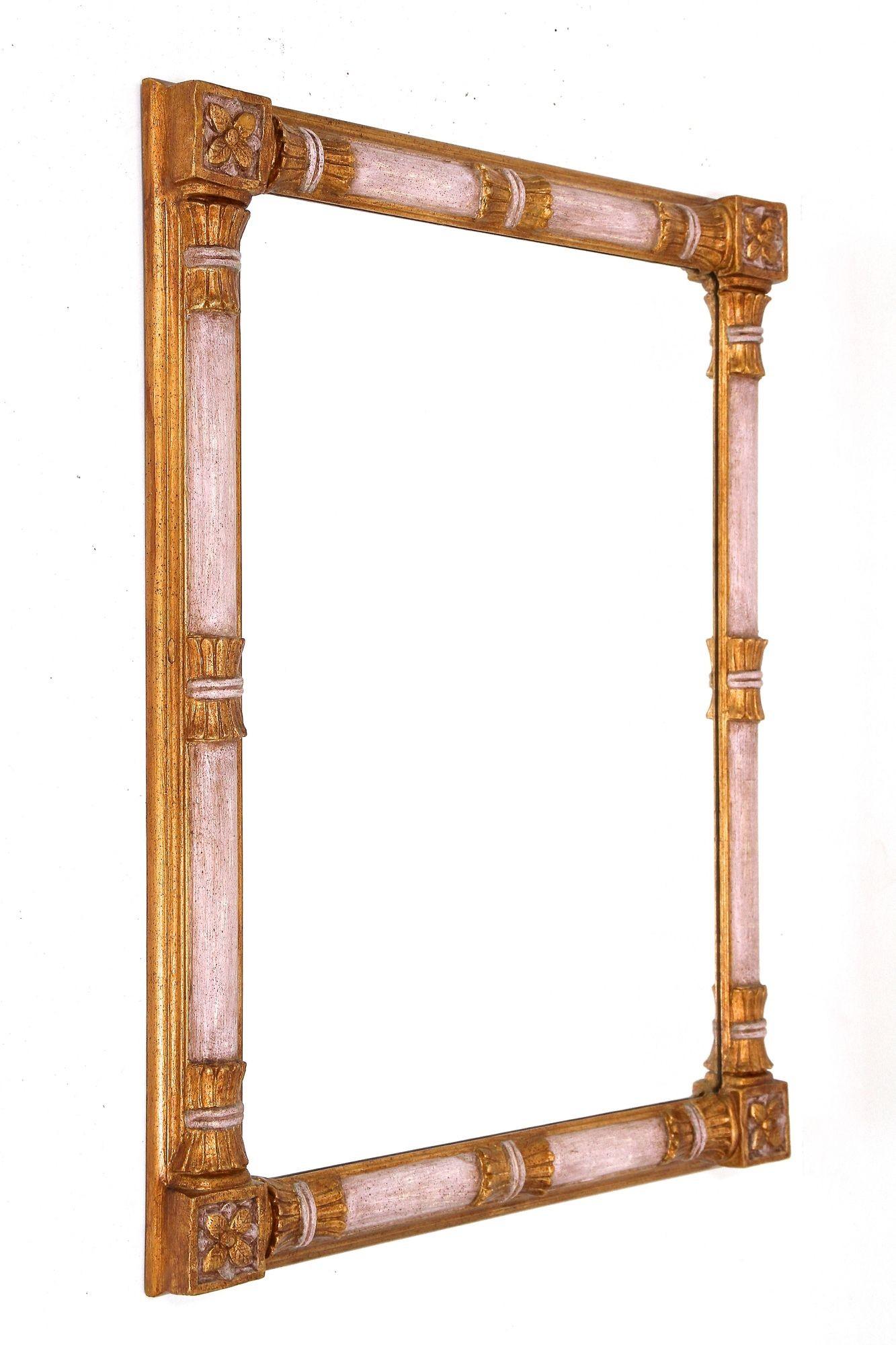 Extraordinary, large gilt wall mirror from the 1950s in Italy. This absolutely amazing looking mid century wall mirror impresses with its broad, very special handcarved frame adorned by amazing looking gilt parts and lovely, light dusty pink