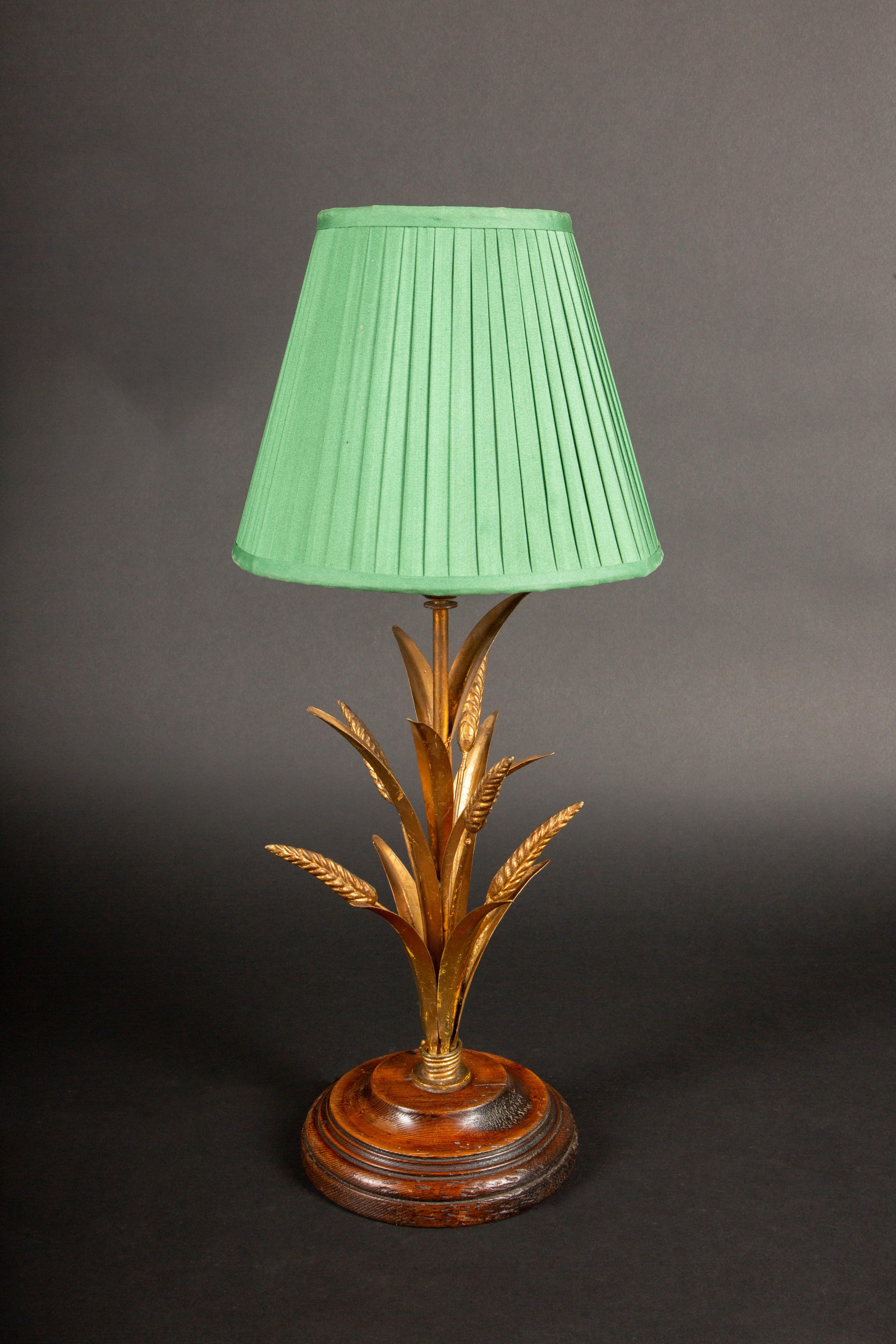A striking mid-century gilt wheat sheath table lamp, mounted on an elegant wooden base. The lamp features a finely detailed bundle of gilt metal wheat stalks, symbolizing abundance and prosperity, arranged in a graceful, upward sweep. The base's
