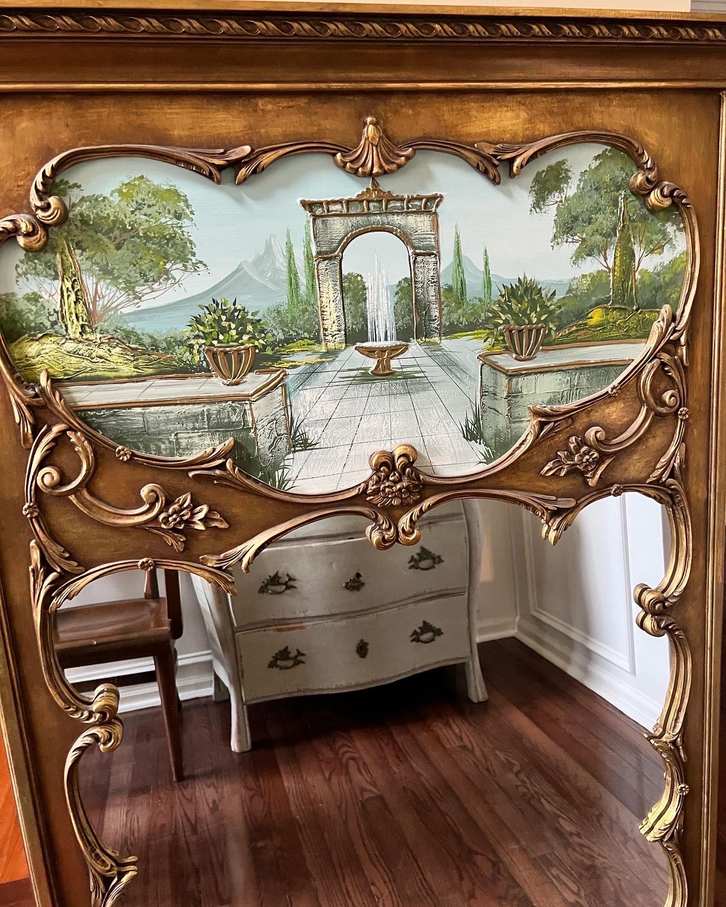 Fabulous vintage Trumeau giltwood mirror with tranquil painting. 

Surrounded by an elaborately carved gold wood frame, the lovely ornamental garden scene offers textural depth and a pleasing color palette highlighted with gold accent. 

This