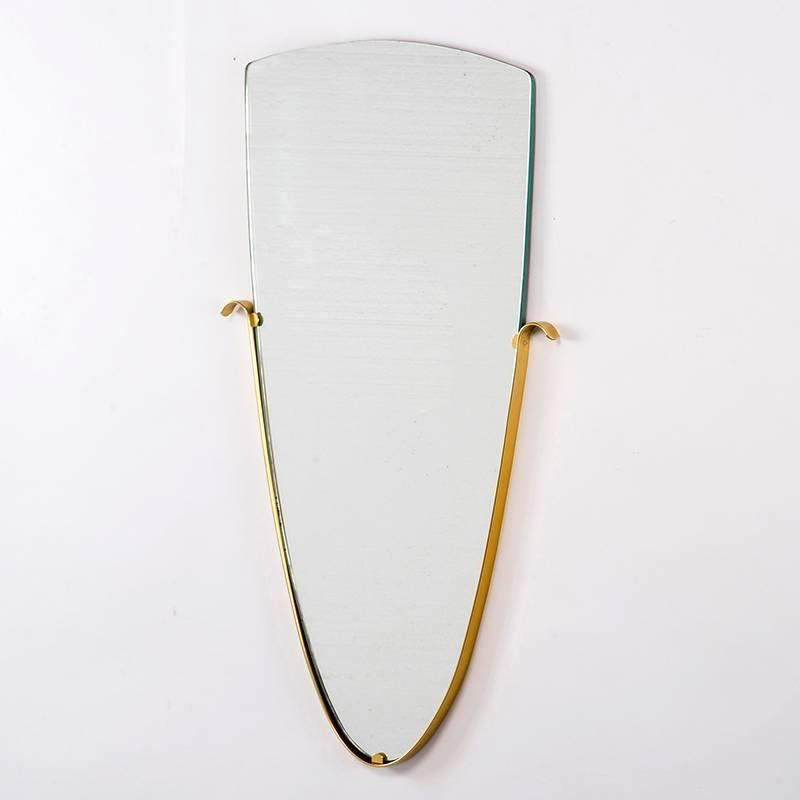 Circa 1960 shield shaped mirror features a slip-in brass frame in the style of Gio Ponti. Unknown maker.   Found in Belgium.
