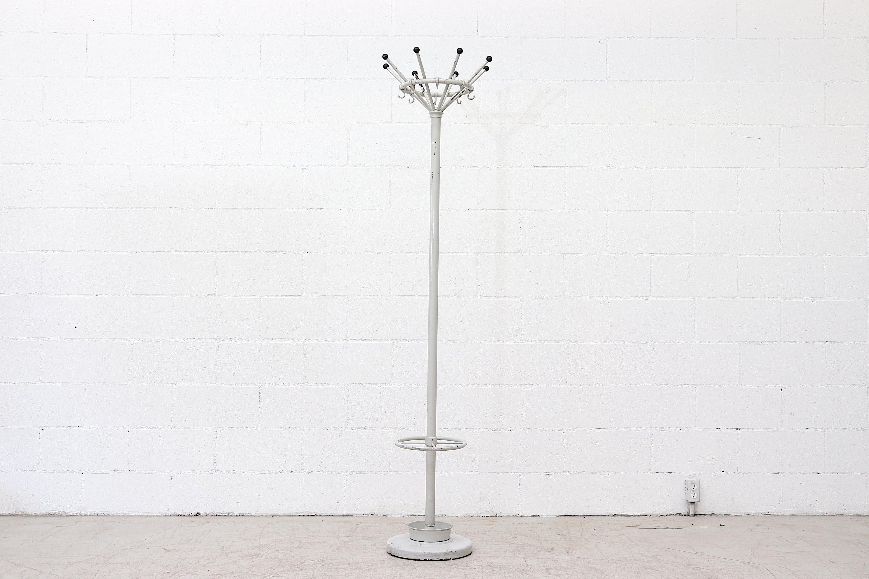Gispen light grey enameled metal coat rack with weighted base and umbrella holder. 8 tubular arms with black synthetic knobs for coats and hats. In original condition with some rust and wear consistent with its age and use and 1 broken hook.