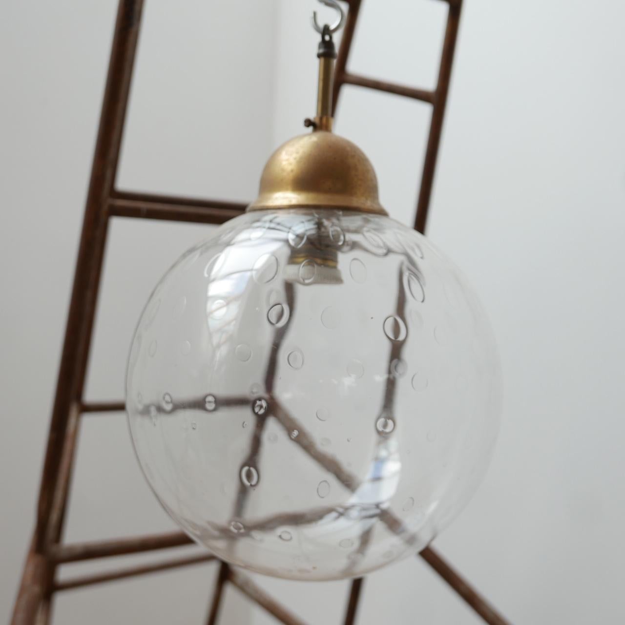 An unusual mid-century pendant light. 

Brass gallery. 

Holland, c1960s. 

The clear glass pendant light is hand blown and has intentional decoration marks reminiscent of a strawberry. 

Dimensions: 40 height x 25 diameter in