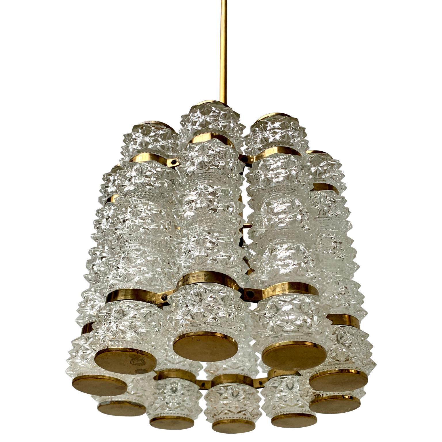 Plafonnier suédois du milieu du siècle. Ce luminaire en laiton et en verre comprend 10 abat-jour cylindriques en verre cristallisé et des accessoires en laiton. Cette lampe vintage est conçue par Orrefors et fabriquée par Tyringe. 

