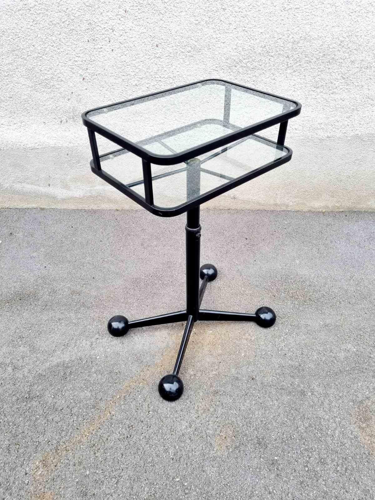 Rare Italian Mid Century  TV Stand / Side Table / End Table was made in Italy in '70s and produced by Arredamenti Allegri Parma.

This Table is made of glass and black metal frame. The Table is on wheels and it is adjustable. The Table is labeled,