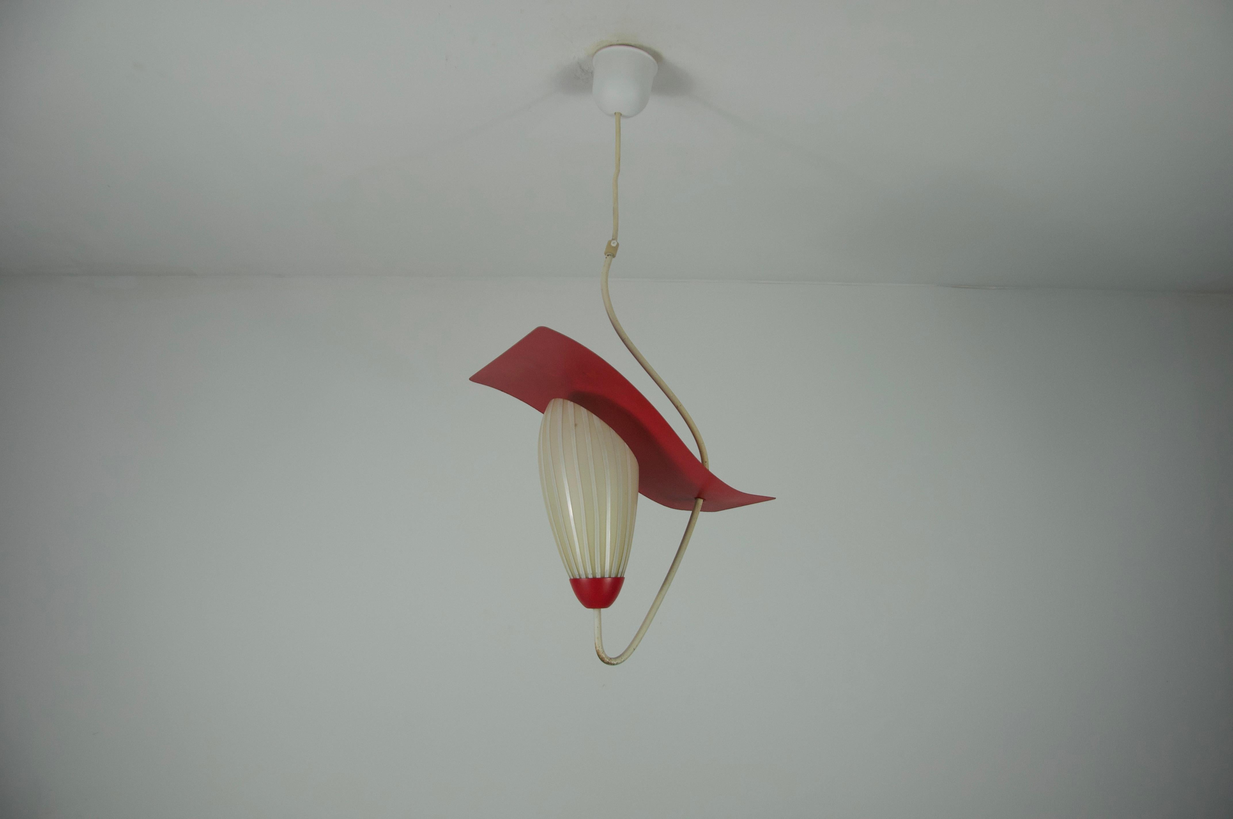 This striking 1960s ceiling lamp from Germany is a bold example of Mid-Century design, blending playful form with dynamic color contrasts. The lamp features a sculptural red metal shade with a softly undulating wave shape, adding a sense of movement