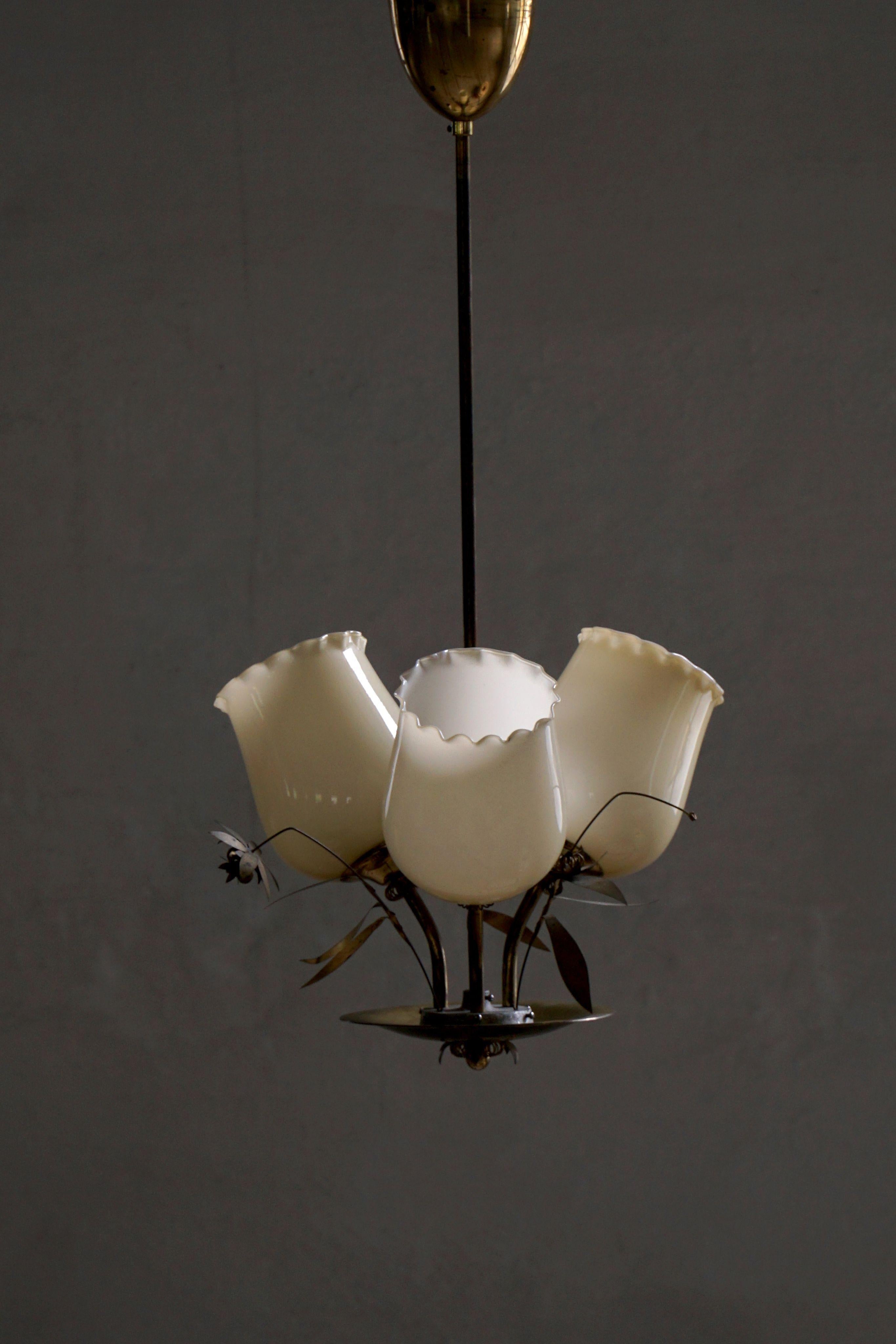 Un eccezionale lampadario degli anni '40 di Stockmann, modello 501-3. Composto da tre bracci in ottone elegantemente arcuati, il pezzo si irradia da uno stelo centrale ornato da delicate foglie in ottone, evocando un senso di natura tradotto in