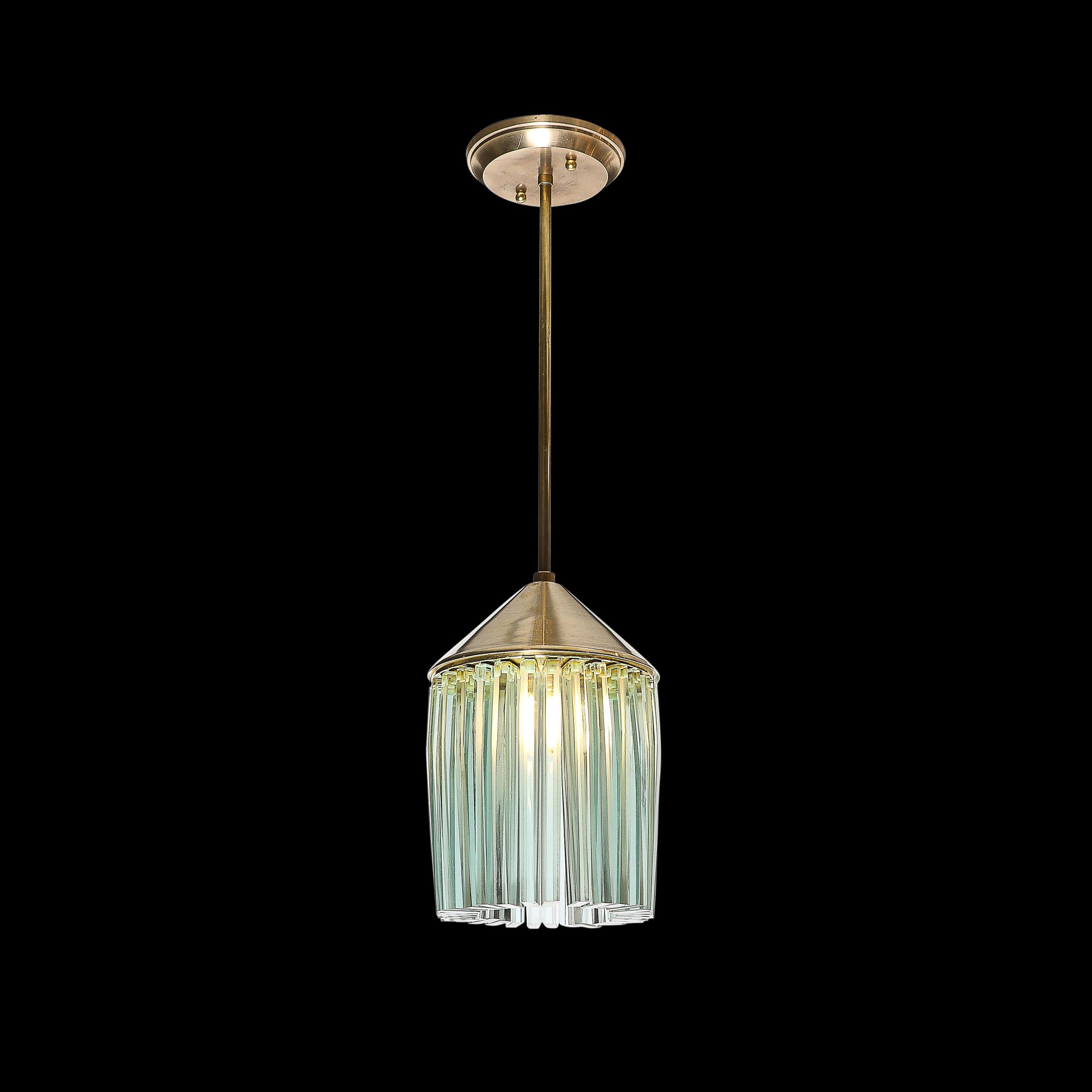This sophisticated and materially dynamic Mid-Century Modernist Glass and Brass Pendant Chandelier in the Manner of Fontana Arte originates from Italy, Circa 1960. This fixture features an array of glass elements angled inwards and regularly spaced,