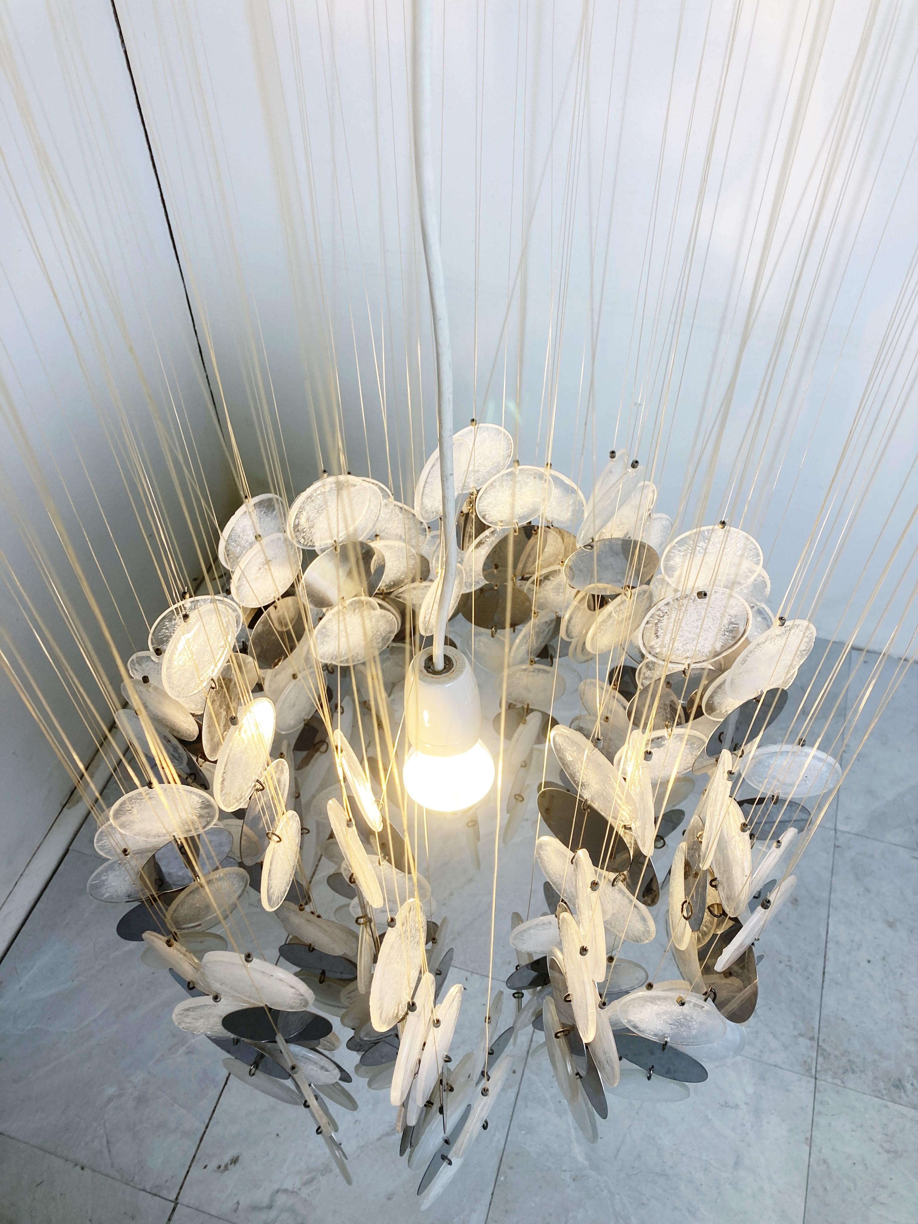 Spectacular chandelier with lots of smoked and white Italian glass discs.

Most of these chandeliers where made with mother of pearl, but these are completely in glass, which is rare.

The chandelier emits a stunning light.

1970s -