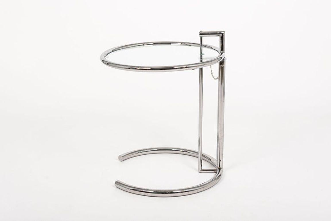 This tubular glass and steel Eileen Gray (attributed) E1027 end table was originally designed by Gray in 1926. The ingenious design features a chrome-plated tubular steel frame with circular glass tabletop that cantilevers over a c-shaped base. The