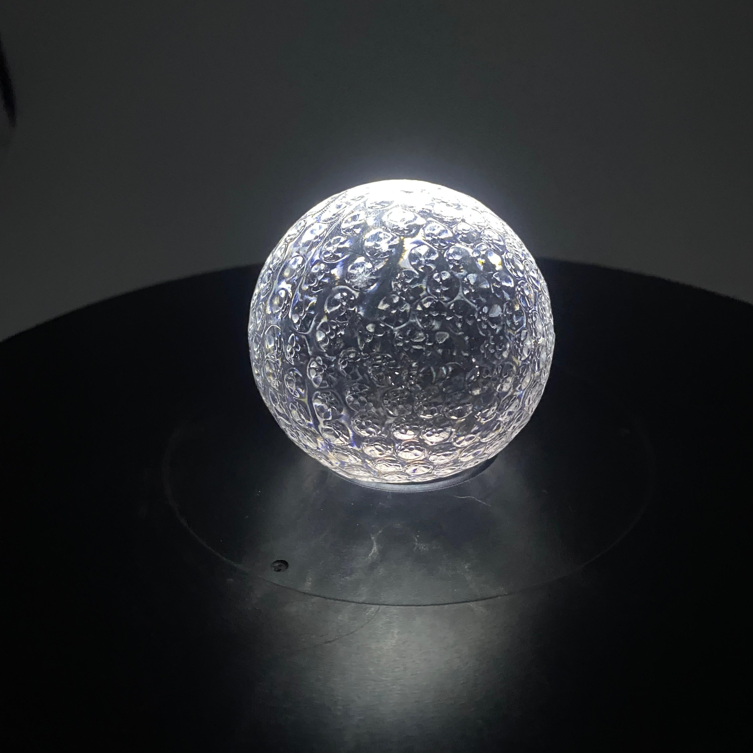 A mid-century glass golf ball paperweight made by Orrefors, circa the 1960s. The Orrefors Sweden sticker is attached to the base. 